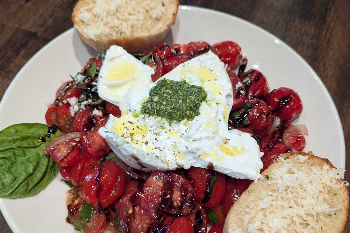 Caprese salad with fresh burrata cheese, borettane (grilled onion), fresh pesto and garlic bread